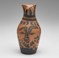 A red earthenware pitcher by Pablo Picasso, decorated with a stylized black image of a bearded man's face, blending traditional ceramic form with modern graphic elements.