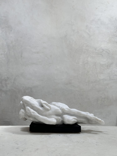 Eva Claessens Dao 2025 marble sculpture of elongated reclining form on dark base against textured wall  